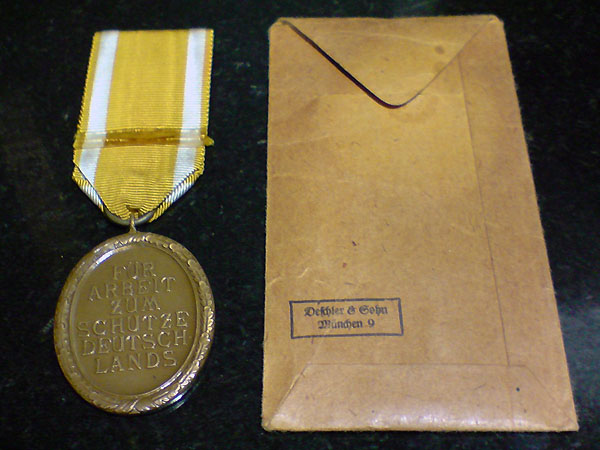 Vista trasera de la Medalla para la construcción y defensa de la muralla Atlántica con sobre de concesión.